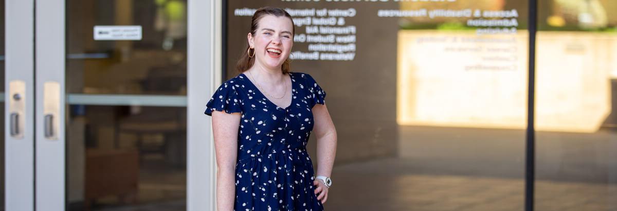 Alexis Rose Young stands smiling in front of the Student Service Center at Pima's West Campus