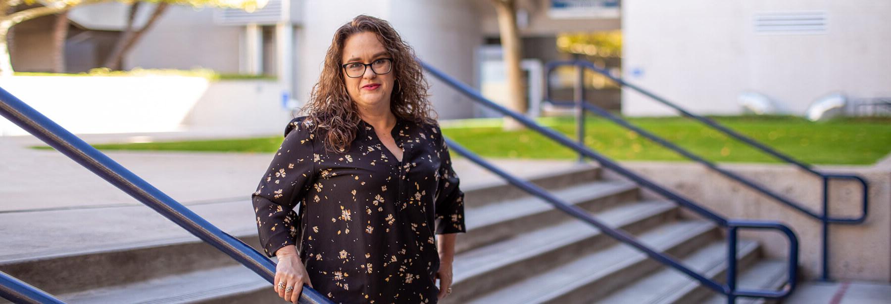 Crystal Robles stands smiling in the courtyard of West Campus