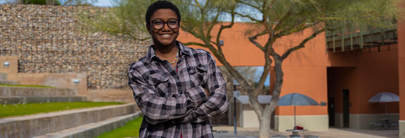 多米尼克财富 stands smiling in a courtyard at Pima's Northwest Campus