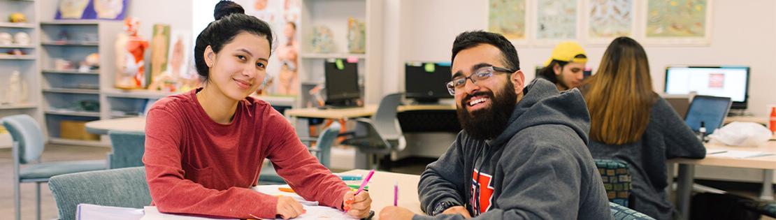 A tutor and student smile for the camera at a PCC library.