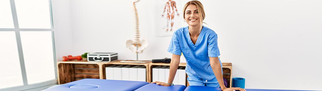 A massage therapist smiles in front of her table