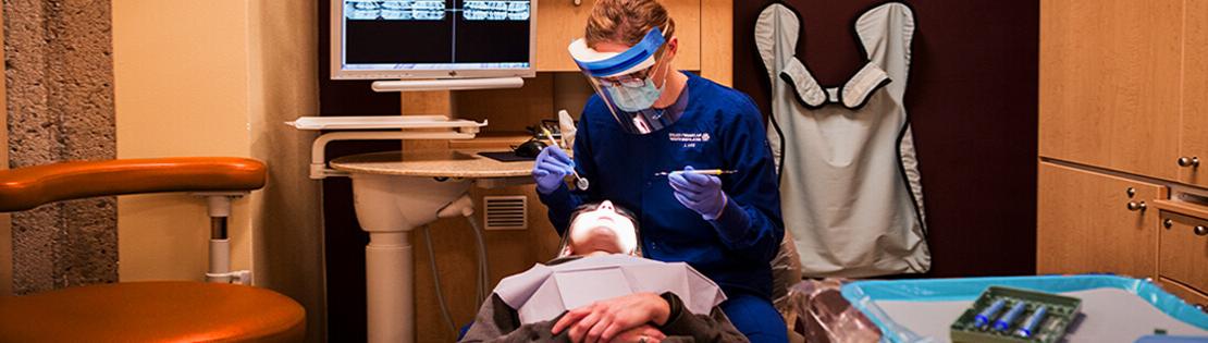 Dental hygiene student examines teeth of a patient